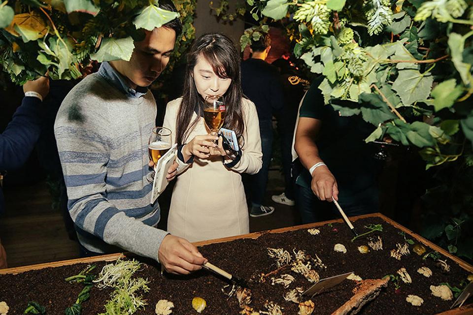 Les invités interagissent avec une installation de dégustation basée sur le sol tout en dégustant des boissons lors d'un événement gastronomique expérientiel du Cirque du Soleil.