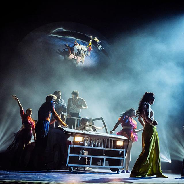 Les artistes du Cirque du Soleil se rassemblent autour d'une scène mobile dans une scène spectaculaire remplie de brouillard et d'éclairages théâtraux.